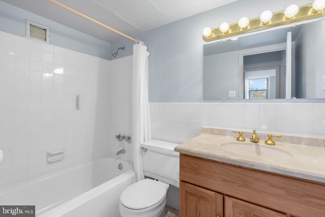 bathroom with visible vents, toilet, shower / bath combo with shower curtain, vanity, and tile walls