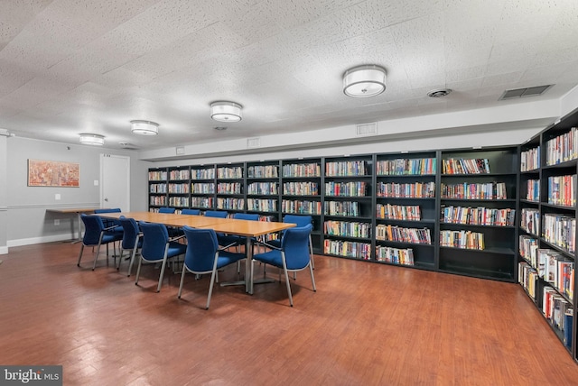 interior space featuring baseboards, a textured ceiling, visible vents, and wood finished floors