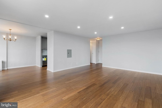 unfurnished living room with a chandelier, wood finished floors, electric panel, and recessed lighting