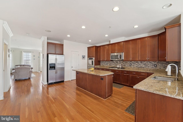 kitchen featuring decorative backsplash, appliances with stainless steel finishes, light stone counters, light wood-style floors, and a sink