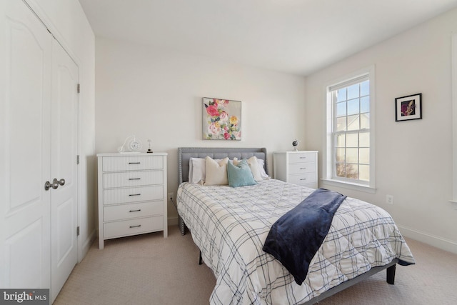 bedroom with light carpet, baseboards, and a closet