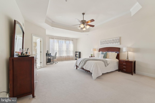 carpeted bedroom featuring ornamental molding, a tray ceiling, baseboards, and a ceiling fan