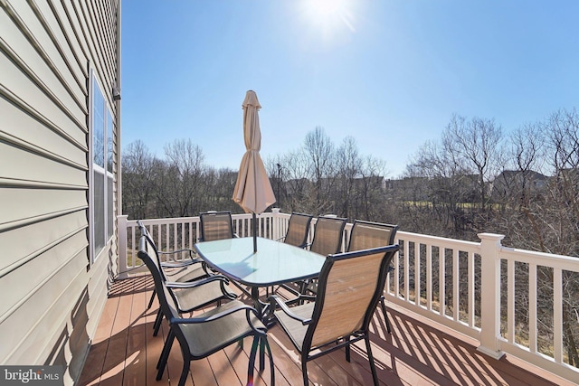 deck featuring outdoor dining area and a view of trees