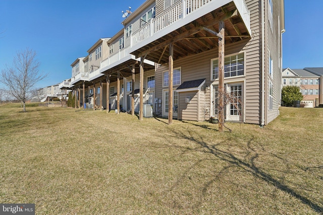 back of house with a residential view, a yard, and central AC unit