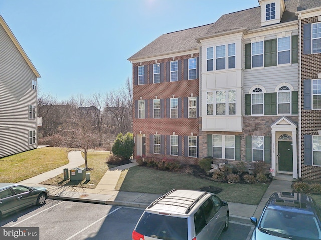 view of front of property with uncovered parking, brick siding, and a front yard
