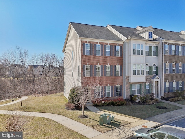townhome / multi-family property featuring a front yard and brick siding