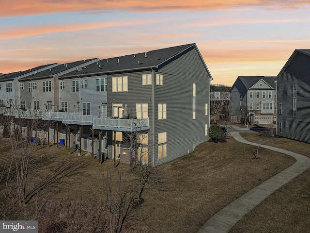 back of property at dusk featuring a yard and a residential view