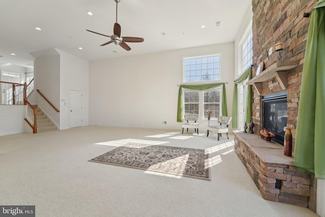 living area featuring carpet floors, recessed lighting, a stone fireplace, and stairs