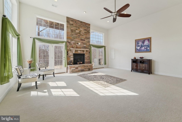 living room featuring carpet floors, a high ceiling, a fireplace, visible vents, and baseboards