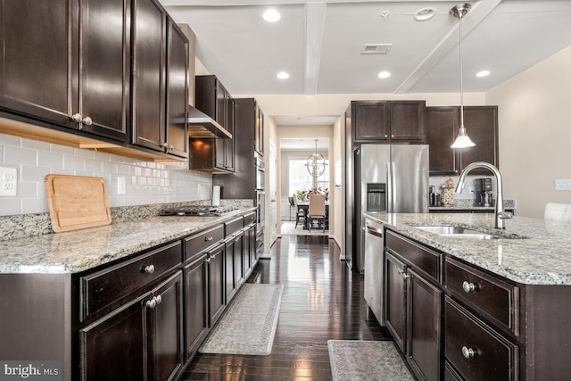 kitchen featuring stainless steel appliances, hanging light fixtures, backsplash, dark wood-type flooring, and a sink