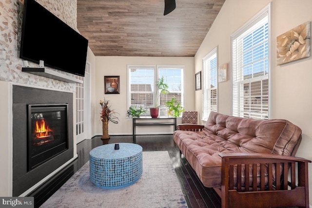 living room with dark wood-style floors, vaulted ceiling, wooden ceiling, and a glass covered fireplace