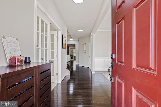 foyer entrance featuring dark wood-style flooring and a decorative wall