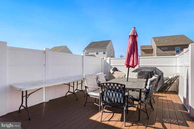 wooden terrace with a fenced backyard, outdoor dining area, and area for grilling