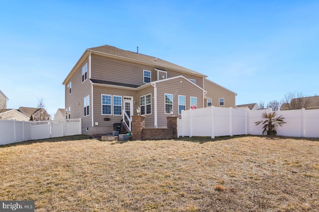 rear view of house with a fenced backyard and a lawn