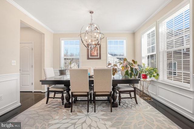 dining space featuring a notable chandelier, crown molding, a decorative wall, and wood finished floors