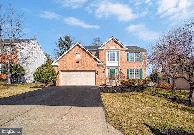 view of front facade with a front yard, brick siding, driveway, and an attached garage