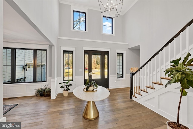 foyer entrance featuring stairs, an inviting chandelier, wood finished floors, and ornamental molding