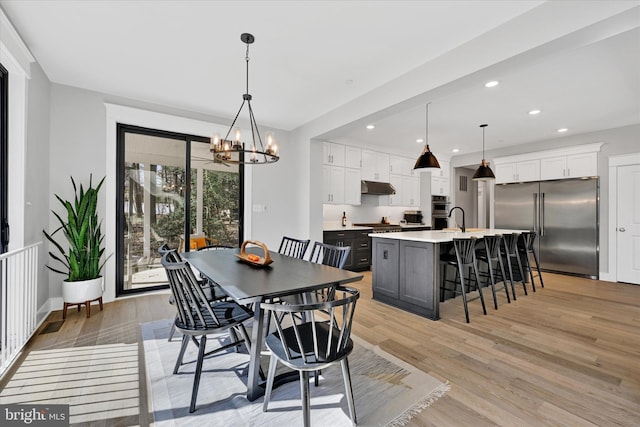 dining room with a notable chandelier, recessed lighting, and light wood finished floors