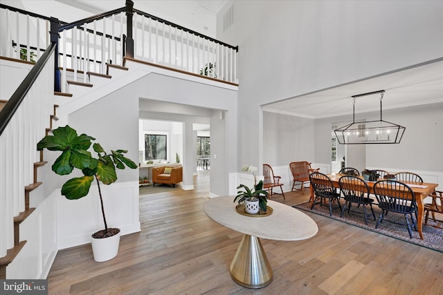 dining space featuring stairway, crown molding, visible vents, and hardwood / wood-style floors