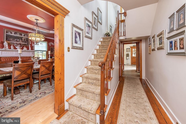 stairs featuring arched walkways, a notable chandelier, baseboards, and wood finished floors