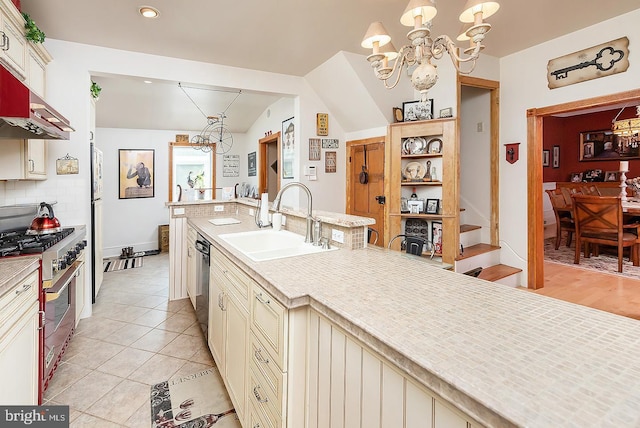 kitchen with a sink, light countertops, cream cabinetry, high end range, and decorative light fixtures