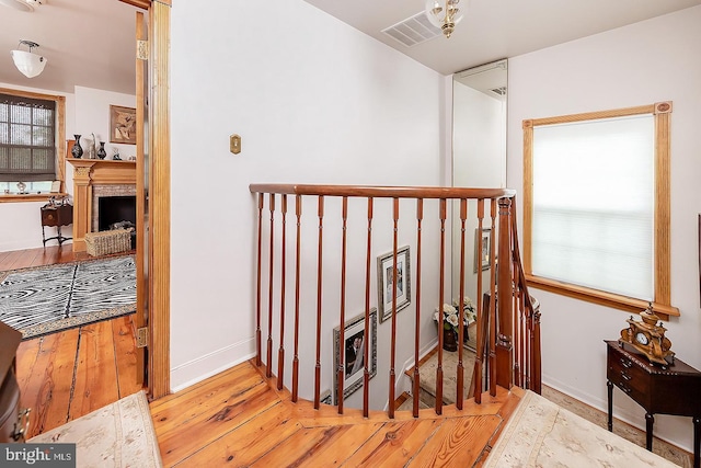 hallway featuring wood-type flooring, heating unit, visible vents, and baseboards