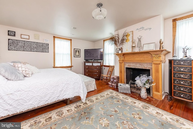 bedroom featuring multiple windows, a fireplace, and wood finished floors