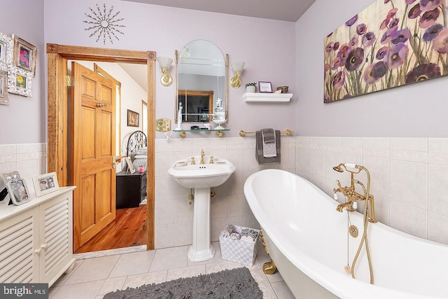 full bathroom with tile patterned flooring, a wainscoted wall, a freestanding bath, and tile walls