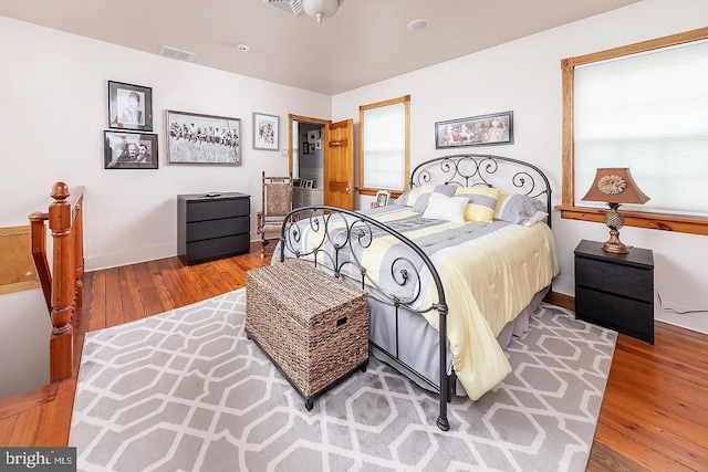 bedroom featuring visible vents, multiple windows, and hardwood / wood-style flooring