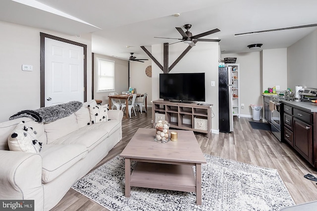 living area with baseboards, a ceiling fan, and light wood-style floors