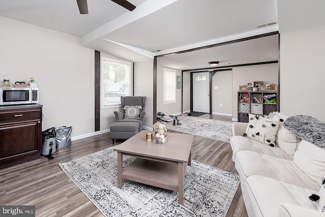 living room with visible vents, light wood-style floors, ceiling fan, beamed ceiling, and baseboards