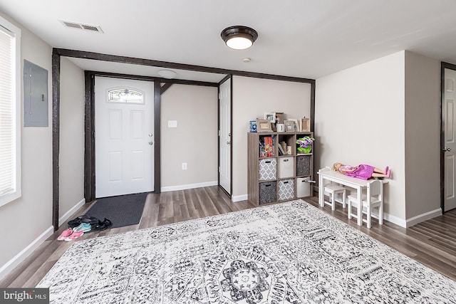 interior space with electric panel, visible vents, baseboards, and wood finished floors