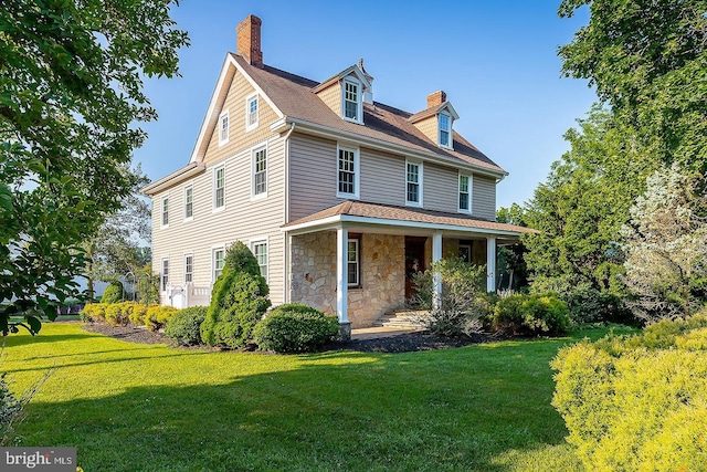 view of front of house featuring stone siding, a chimney, and a front yard