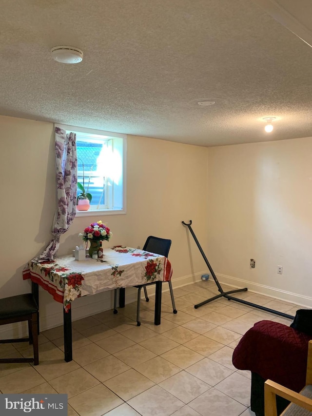 interior space featuring light tile patterned floors, baseboards, and a textured ceiling