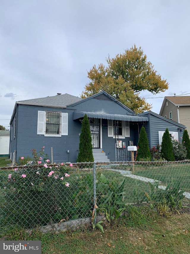 view of front of home with a fenced front yard, concrete block siding, and a front yard