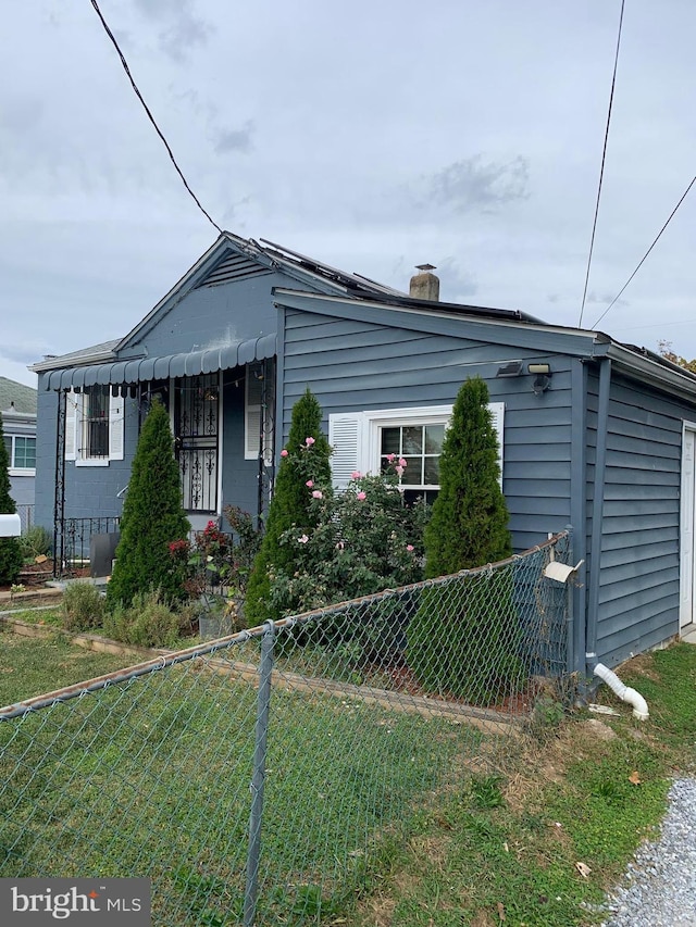 view of front of home featuring fence, a chimney, and a front lawn