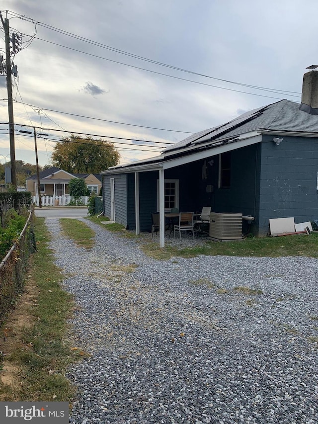 exterior space featuring a shingled roof, concrete block siding, and fence