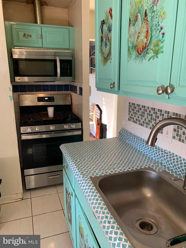 kitchen featuring light tile patterned floors, stainless steel appliances, light countertops, decorative backsplash, and a sink