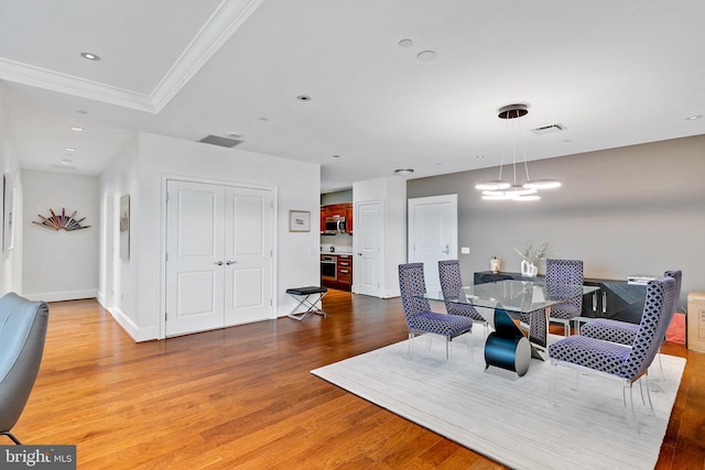 dining space with baseboards, visible vents, wood finished floors, crown molding, and recessed lighting