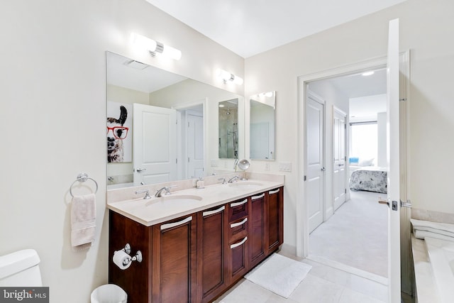 ensuite bathroom featuring a sink, double vanity, connected bathroom, and toilet