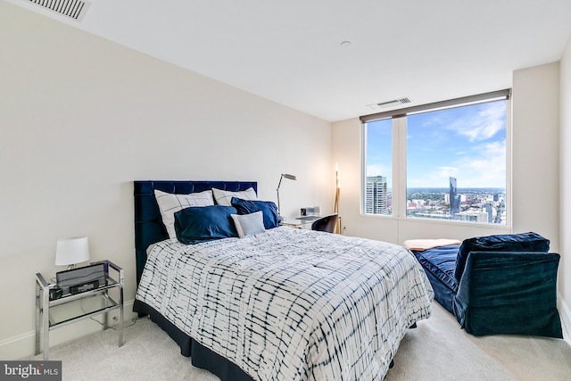 bedroom featuring light colored carpet, a city view, visible vents, and baseboards