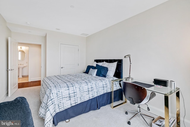 bedroom featuring baseboards, a sink, and light colored carpet