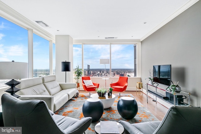 living area featuring a wealth of natural light, light wood-style flooring, visible vents, and crown molding