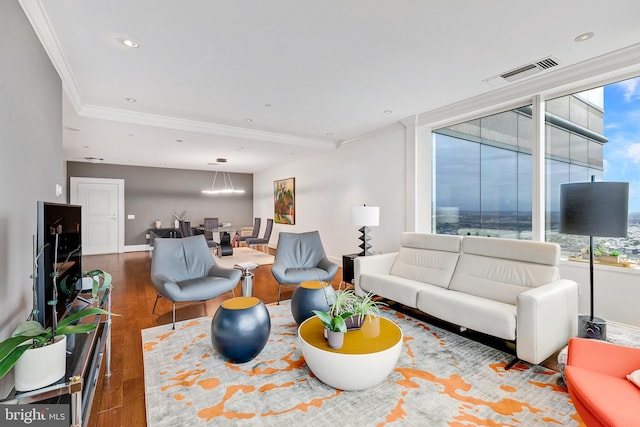 living room featuring a healthy amount of sunlight, visible vents, crown molding, and dark wood-style flooring