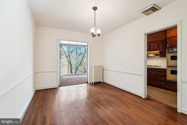 unfurnished dining area with visible vents, dark wood finished floors, baseboards, radiator heating unit, and a chandelier