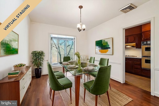 dining room featuring dark wood finished floors, visible vents, and an inviting chandelier