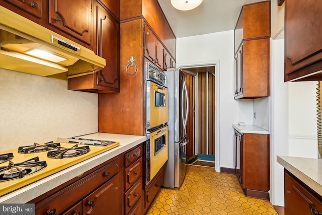 kitchen with light countertops, white gas cooktop, freestanding refrigerator, and under cabinet range hood