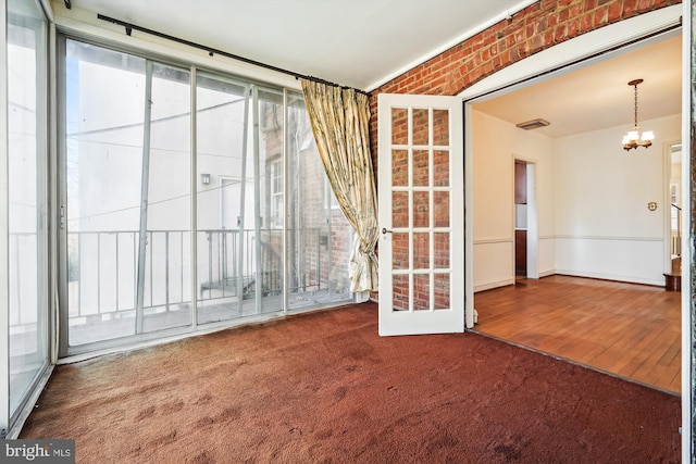 empty room with carpet flooring, visible vents, and an inviting chandelier