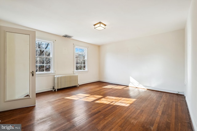 unfurnished room with baseboards, hardwood / wood-style floors, visible vents, and radiator