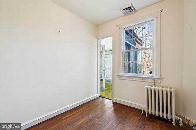 unfurnished room with radiator, hardwood / wood-style flooring, baseboards, and visible vents